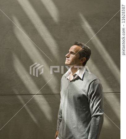 Man looking up into light next to wall 11628387