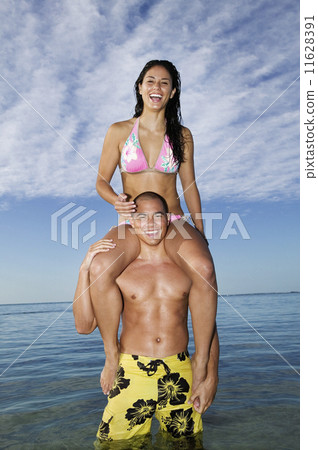Pacific Islander woman sitting on boyfriend's shoulders 11628391