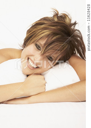 Woman laying with arms around pillow 11628428