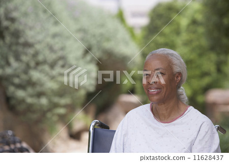 Senior African woman in hospital gown and wheelchair outdoors 11628437