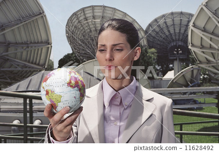 Hispanic businesswoman holding globe in front of satellite dishes 11628492