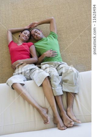 Young couple on floor with feet on sofa Young couple on floor with feet on sofa 11628494