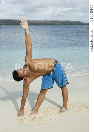Hispanic man practicing yoga at beach 11628495