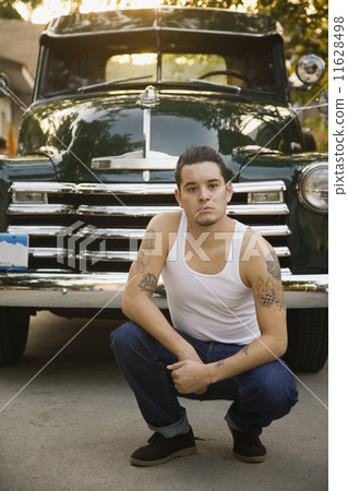 Hispanic man with tattoos in front of truck 11628498