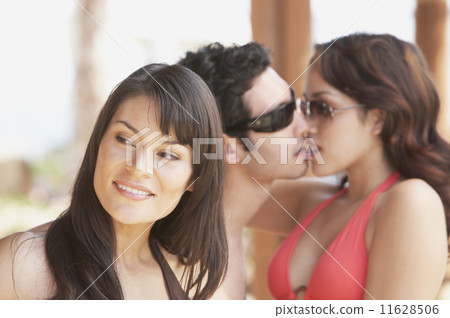 Hispanic woman with young Hispanic couple kissing in background  11628506
