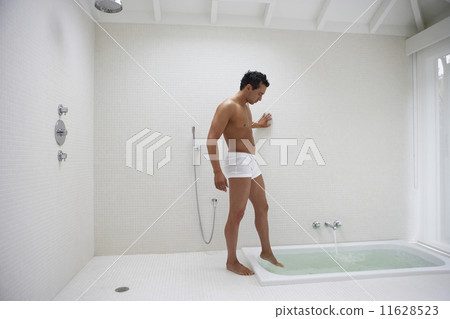 Man wearing underwear and putting foot in bath water 11628523