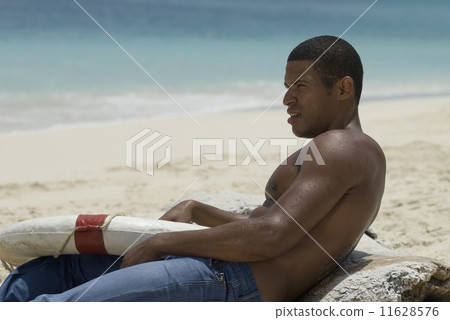 Hispanic man holding life preserver at beach 11628576