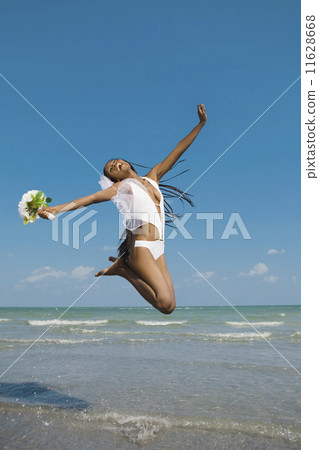 African bride jumping in ocean surf 11628668