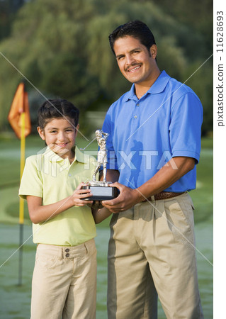 Hispanic father and daughter holding golf trophy Hispanic father and daughter holding golf trophy 11628693