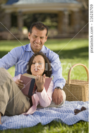 Hispanic couple reading on picnic blanket Hispanic couple reading on picnic blanket 11628709
