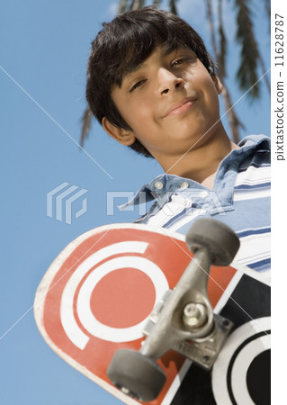 Hispanic boy holding skateboard Hispanic boy holding skateboard 11628787
