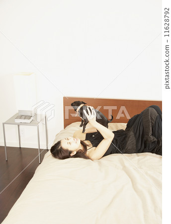 Asian woman holding dog on bed Asian woman holding dog on bed 11628792