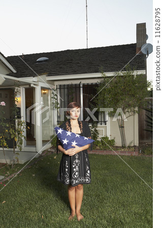 Mixed Race woman holding folded American flag 11628795