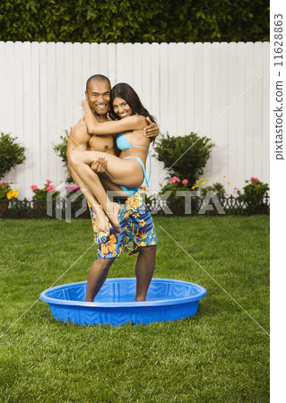 Multi-ethnic couple standing in kiddie pool 11628863