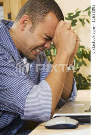 Frustrated Pacific Islander man next to laptop Frustrated Pacific Islander man next to laptop 11628892