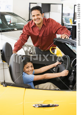 Hispanic father and son looking at new car 11628939
