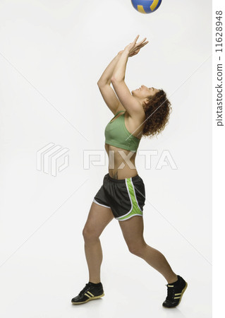 Mixed Race woman bouncing volleyball 11628948