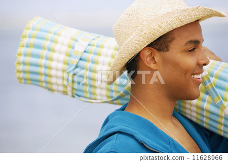 Hispanic man carrying beach mat 11628966