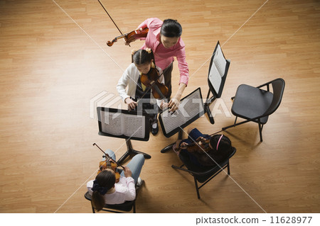 Asian female music teacher helping student play violin 11628977