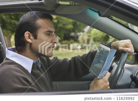 Hispanic man looking at map in car 11628992