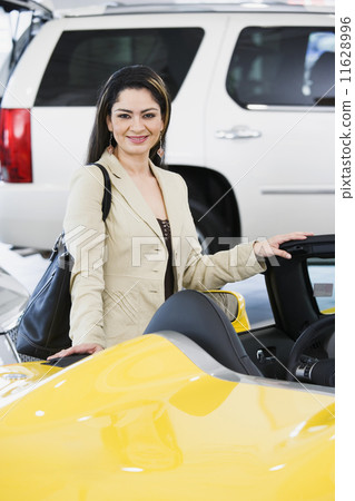 Hispanic woman looking at new car 11628996