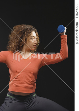 Mixed Race woman holding dumbbell Mixed Race woman holding dumbbell 11629029