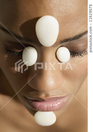 African woman receiving spa stone treatment on face African woman receiving spa stone treatment on face 11629078
