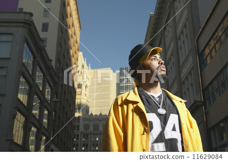 Low angle view of young African man standing in urban area  11629084