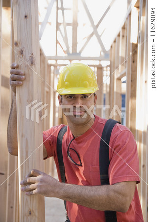 Mixed Race male construction worker holding lumber 11629093