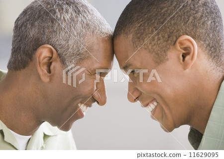 African American father and adult son touching foreheads African American father and adult son touching foreheads 11629095