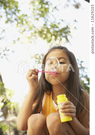 Hispanic girl blowing bubbles outdoors Hispanic girl blowing bubbles outdoors 11629103
