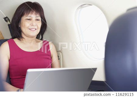 Asian businesswoman working on airplane Asian businesswoman working on airplane 11629115