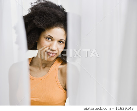 African American woman through parted curtains African American woman through parted curtains 11629142