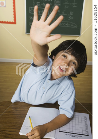 Boy with hand raised in classroom 11629154