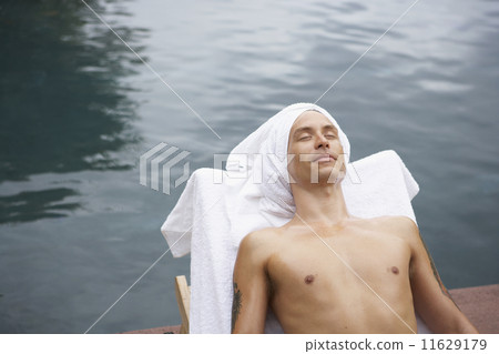 Man in lounge chair next to water 11629179