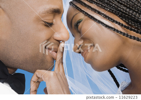 African bride touching groom's lips 11629223