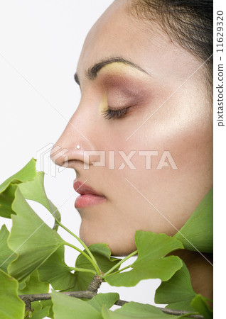 Indian woman's face next to gingko biloba plant Indian woman's face next to gingko biloba plant 11629320