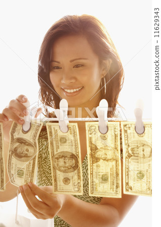 Asian woman hanging money on clothes line Asian woman hanging money on clothes line 11629343