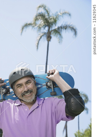 Hispanic man holding skateboard Hispanic man holding skateboard 11629345