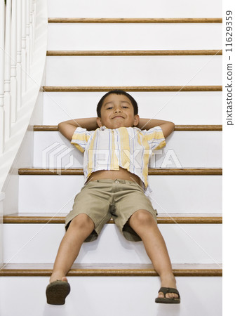 Hispanic boy laying on stairs Hispanic boy laying on stairs 11629359