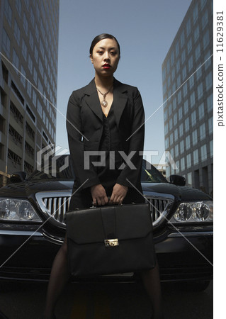 Asian businesswoman with briefcase next to car 11629381