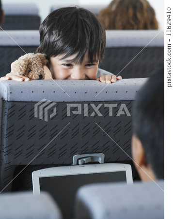 Young boy peeking over seat in airplane 11629410