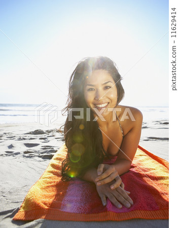 Portrait of woman laying on towel at beach Portrait of woman laying on towel at beach 11629414