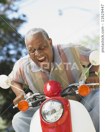 Middle-aged African man riding a scooter  11629447