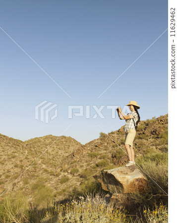 Hispanic woman talking photograph of countryside Hispanic woman talking photograph of countryside 11629462