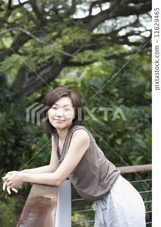 Asian woman leaning on balcony railing Asian woman leaning on balcony railing 11629465