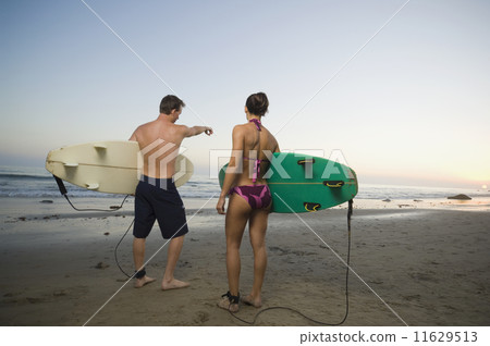 Multi-ethnic couple holding surfboards 11629513