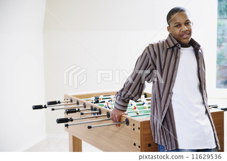 Boy standing beside foosball table Boy standing beside foosball table 11629536