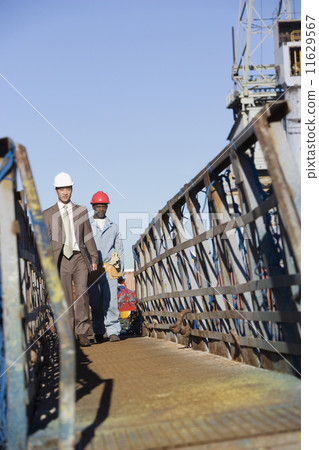 Multi-ethnic businessman and construction worker walking 11629567