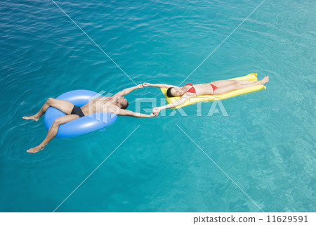 Multi-ethnic couple on floats in water 11629591